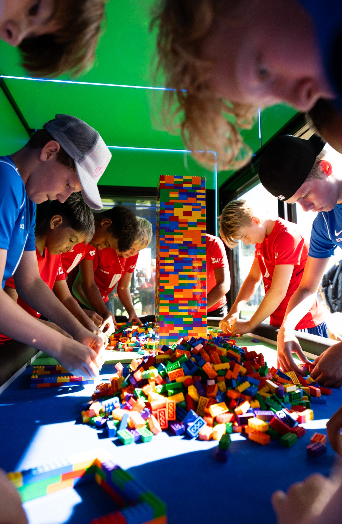 Teams building with colourful LEGO bricks around a shared table